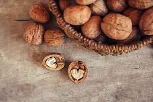 Walnuts in a round wicker basket on a wooden background. Top view. Copy, empty space for text photo
