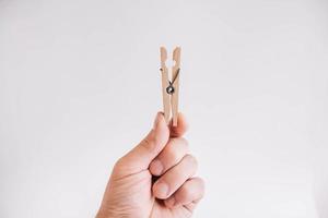 Male hand holding wooden clothespin on white background photo