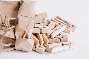 Wooden clothespins in paper bag with rope on white background. View from above. Place for your text photo