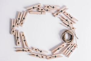 Wooden clothespins with rope on white background. View from above. Place for your text photo