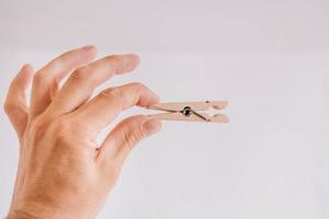 Male hand holding wooden clothespin on white background photo