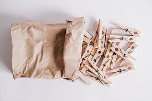 Wooden clothespins in paper bag on white background. View from above. Place for your text photo