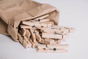 pinzas de madera en bolsa de papel sobre fondo blanco. lugar para tu texto foto