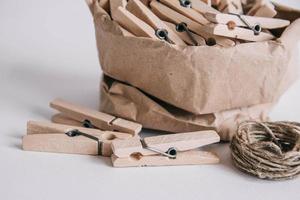 Wooden clothespins in paper bag with rope on white background. Place for your text photo