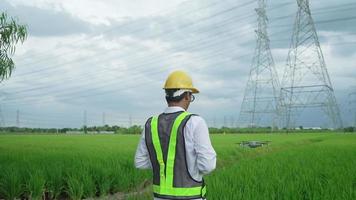 elektrotechnici in gele veiligheidshelmen drones worden gebruikt om krachtige elektrische palen te inspecteren. gelegen in een uitgestrekt grasland video