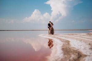 chica y chico en la orilla de un lago salado rosa foto