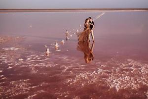 girl and a guy on the shore of a pink salt lake photo