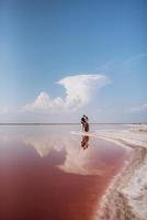 girl and a guy on the shore of a pink salt lake photo