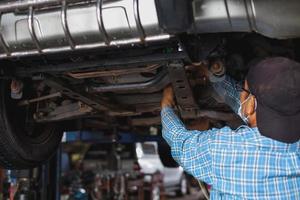 The mechanic is checking the undercarriage of the car. photo