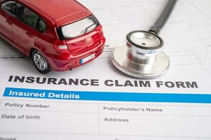 Stethoscope with red car on Insurance  claim accident car form, Car loan, insurance and leasing time concepts. photo