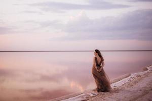 niña en la orilla de un lago salado rosa foto