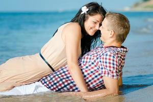 un chico y una chica caminan por la orilla del mar foto