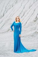 blonde girl in a blue dress with blue eyes in a granite quarry photo