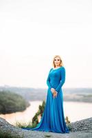 blonde girl in a blue dress with blue eyes in a granite quarry photo