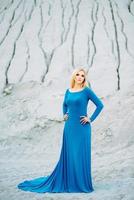 blonde girl in a blue dress with blue eyes in a granite quarry photo