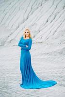 blonde girl in a blue dress with blue eyes in a granite quarry photo