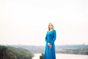 blonde girl in a blue dress with blue eyes in a granite quarry photo