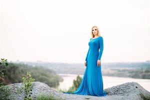 blonde girl in a blue dress with blue eyes in a granite quarry photo