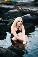 blonde girl in a black dress with blue eyes on the coast of the river photo