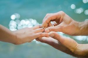 guy's hand puts an wedding ring on a girl's photo