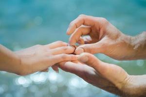 guy's hand puts an wedding ring on a girl's photo