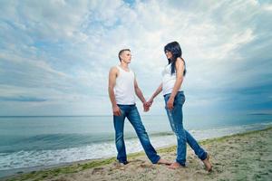 guy and a girl in jeans and white t-shirts on the beach photo