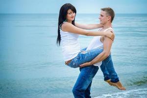 chico y una chica en jeans y camisetas blancas en la playa foto