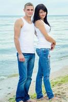 chico y una chica en jeans y camisetas blancas en la playa foto