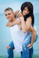 chico y una chica en jeans y camisetas blancas en la playa foto