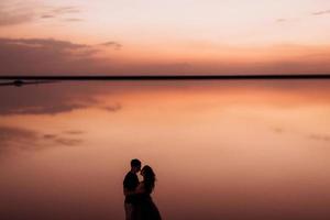 girl and a guy on the shore of a pink salt lake photo