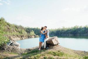 a young couple a guy and a girl are walking near a mountain lake surrounded photo