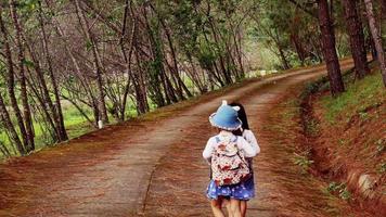 deux petites sœurs se tenant la main et courant le long de la route de la forêt de pins par une journée ensoleillée.