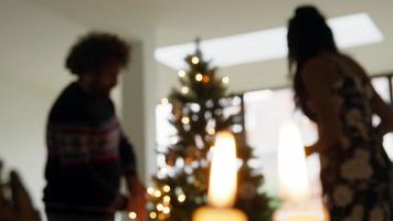 Woman and man decorating Christmas tree with lit lights