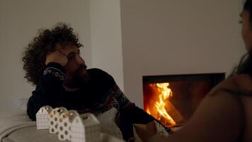 Man talks with woman sitting on couch next to fireplace video