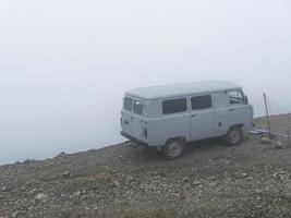 Car on the brink of an abyss in the fog of the clouds. Caucasus mountains photo