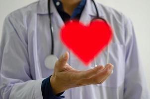 mano del médico con el icono de corazón rojo. enviar aliento a médicos, enfermeras y personal médico foto
