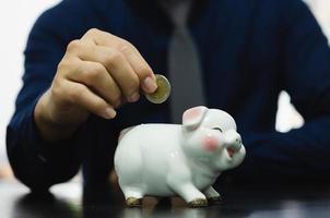 Saving money drops the piggy bank for investment or buying a fund or using it in an emergency. Men's hands are dropping money at the piggy bank. Financial business, investment concept. photo
