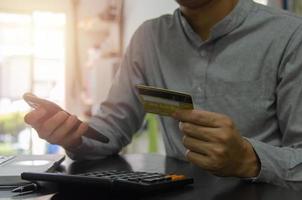 hombre que sostiene una tarjeta de crédito y un teléfono celular para pagar bienes o servicios en línea o comprar en línea. concepto de negocio financiero foto