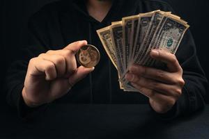 dinero y monedas de oro doge en la mano del hombre de capucha negra foto