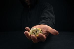 un bitcoin dorado en la mano de un hombre misterioso.