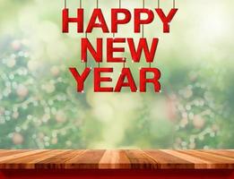 Feliz año nuevo palabra de madera roja colgando sobre una mesa de mármol foto