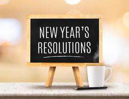 New year Resolutions word on Blackboard with easel on marble table photo