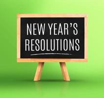 New year's resolutions word on Blackboard with easel on vivid green