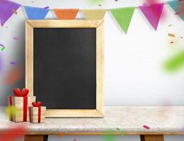 Blackboard with gift box and colorful flag banner on marble table at white wall photo