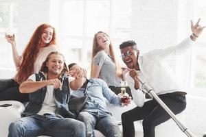 Time for a singing. Office friends have cheerful time sitting and laying on the white sofa photo