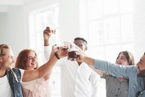 fiesta todo el día. compañeros de equipo bebiendo whisky y riendo por un trato exitoso foto