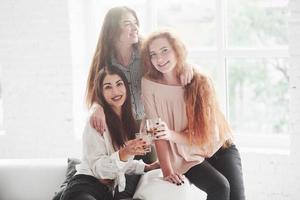 Foto de tres niñas de interior sosteniendo vasos de whisky y sonriendo