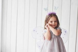 Shy and holding hands to the face. Beautiful little girl with fairy costume having fun posing for the pictures photo