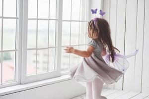 foto en movimiento. linda niña en el vestido de cuento de hadas yendo a las ventanas para mirar lo que hay afuera