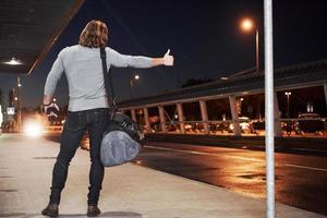 Photo from the back. Guy with blonde hair trying to catch the car